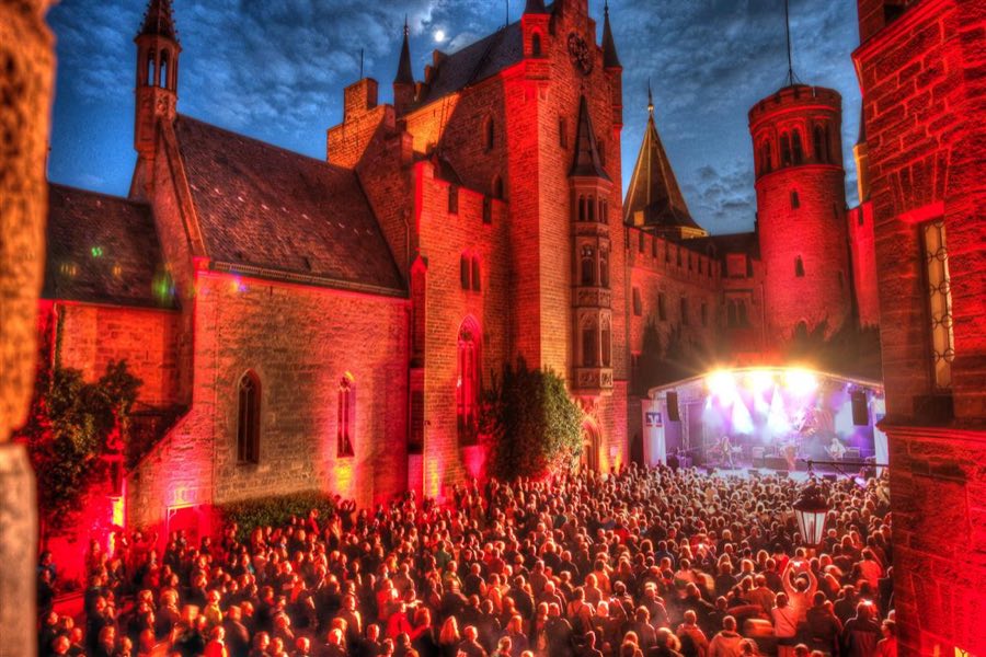 Burghof bei Nacht mit beleuchteter Bühne und Publikum